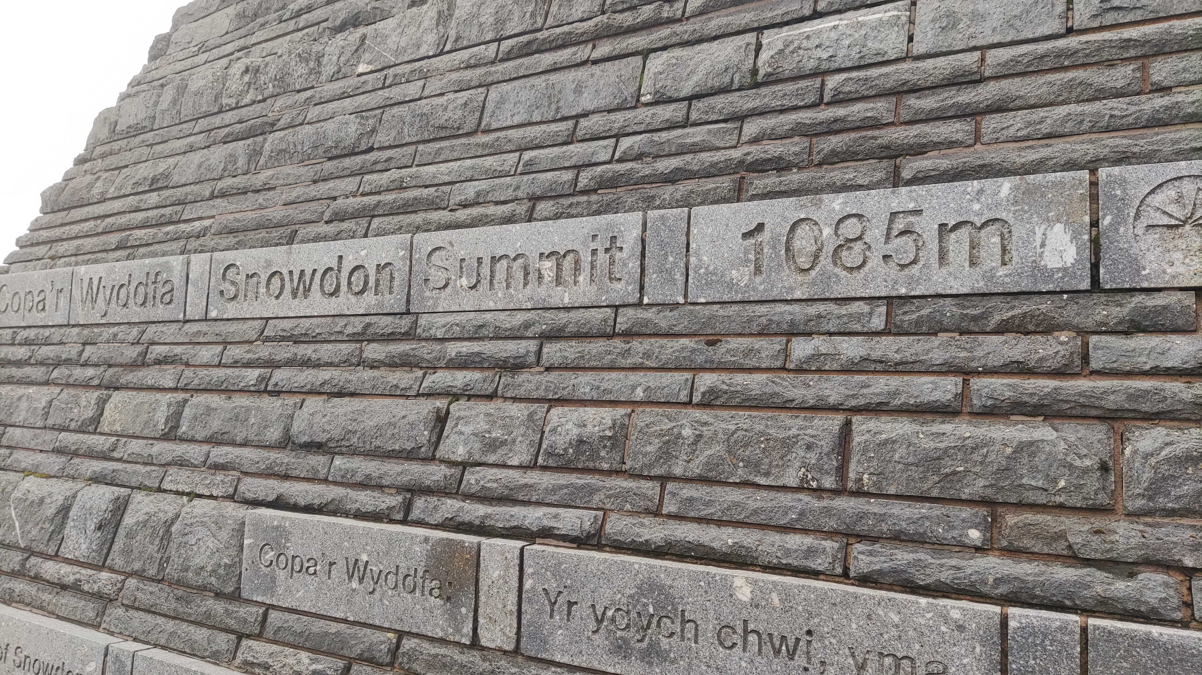 A picture of Snowdon Summit marker with place names and height of summit